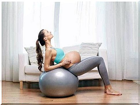 A pregnant woman using a large size ball.