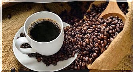 A coffee cup with coffee beans lying around