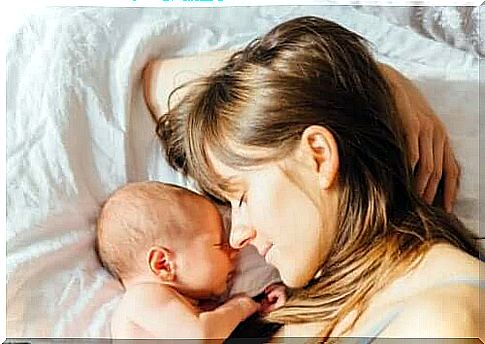 A mother sleeping with her newborn baby.