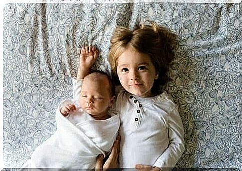 A baby and a little boy lying in bed.