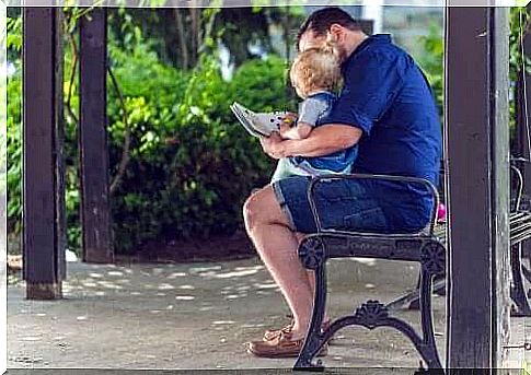 A man and a baby looking in a book.